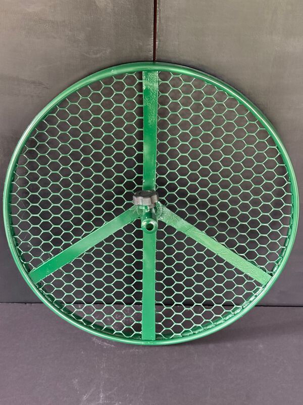 The Cola Cultivator from above: a green circular frame filled with hexagonal netting, three flat spokes meeting at a central hub with a black hand screw